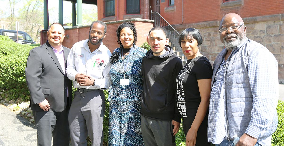 A group of six people standing outside together. They are all looking at the camera and smiling.