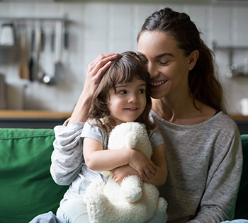 A woman smiling with a young daughter on her lap.