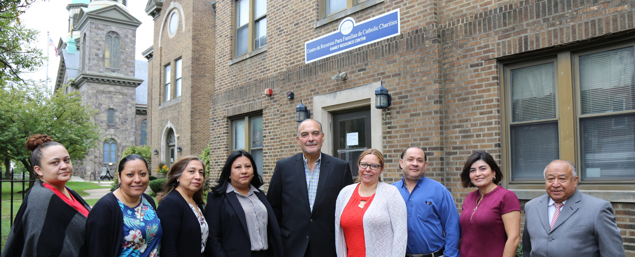 The team at El Centro, six women and three men, stand in yard of the office.