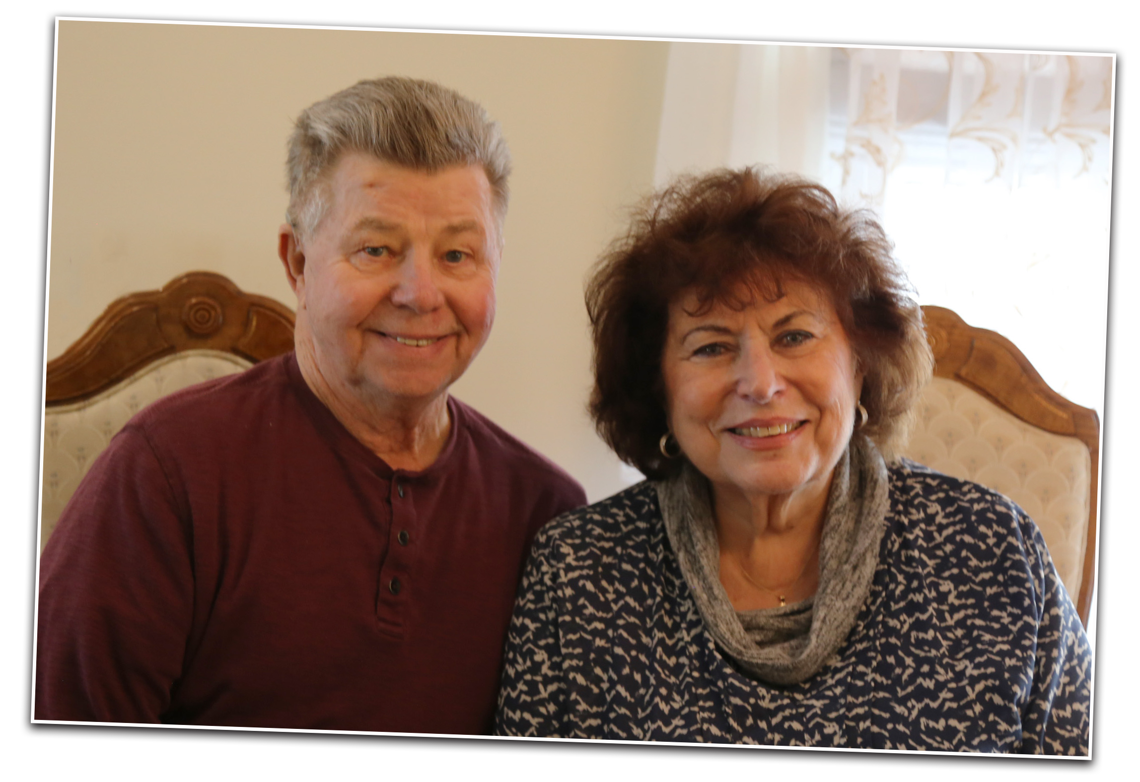 A older man and woman seated side by side smiling.