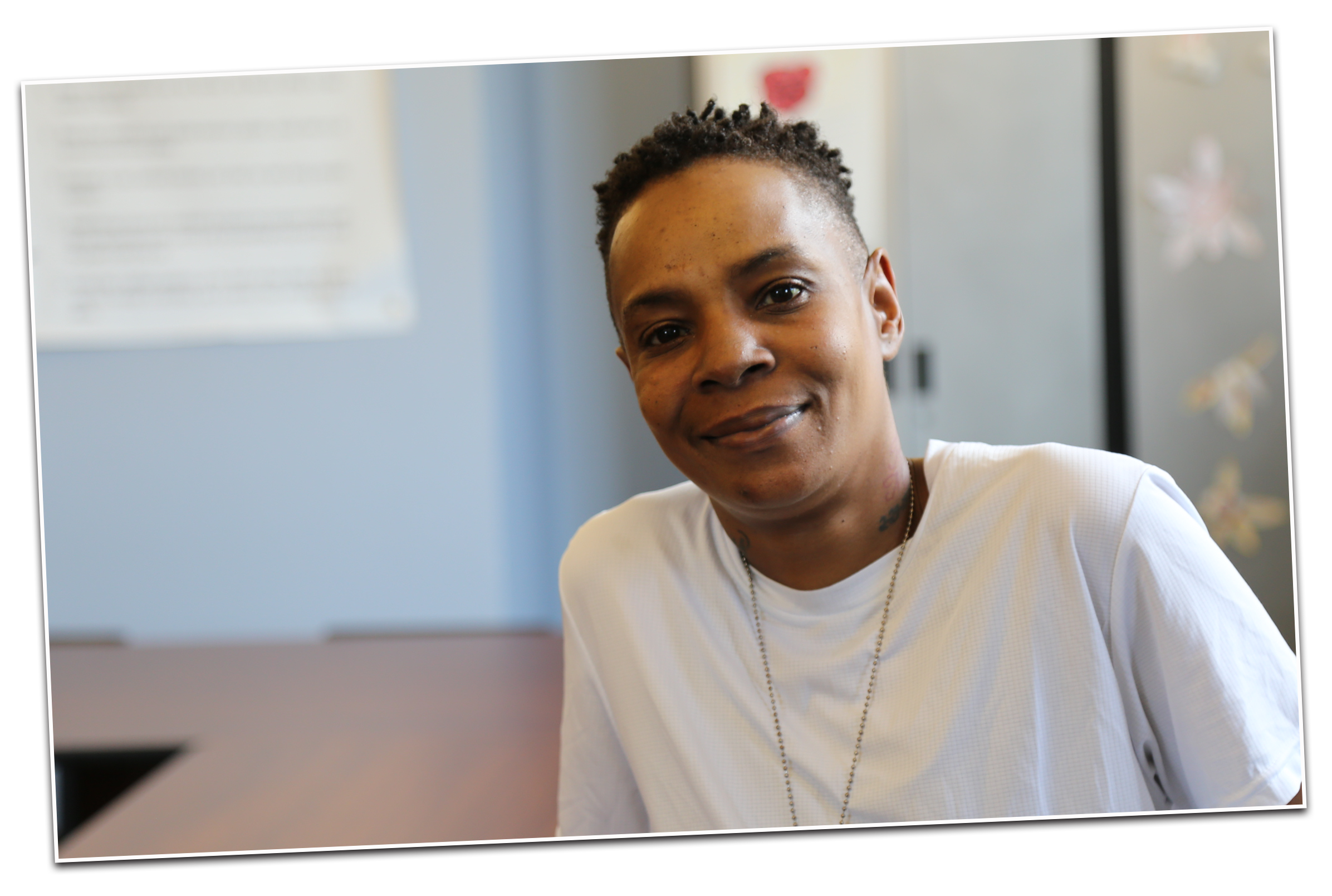 A young black woman with short hair looking at the camera smiling. 